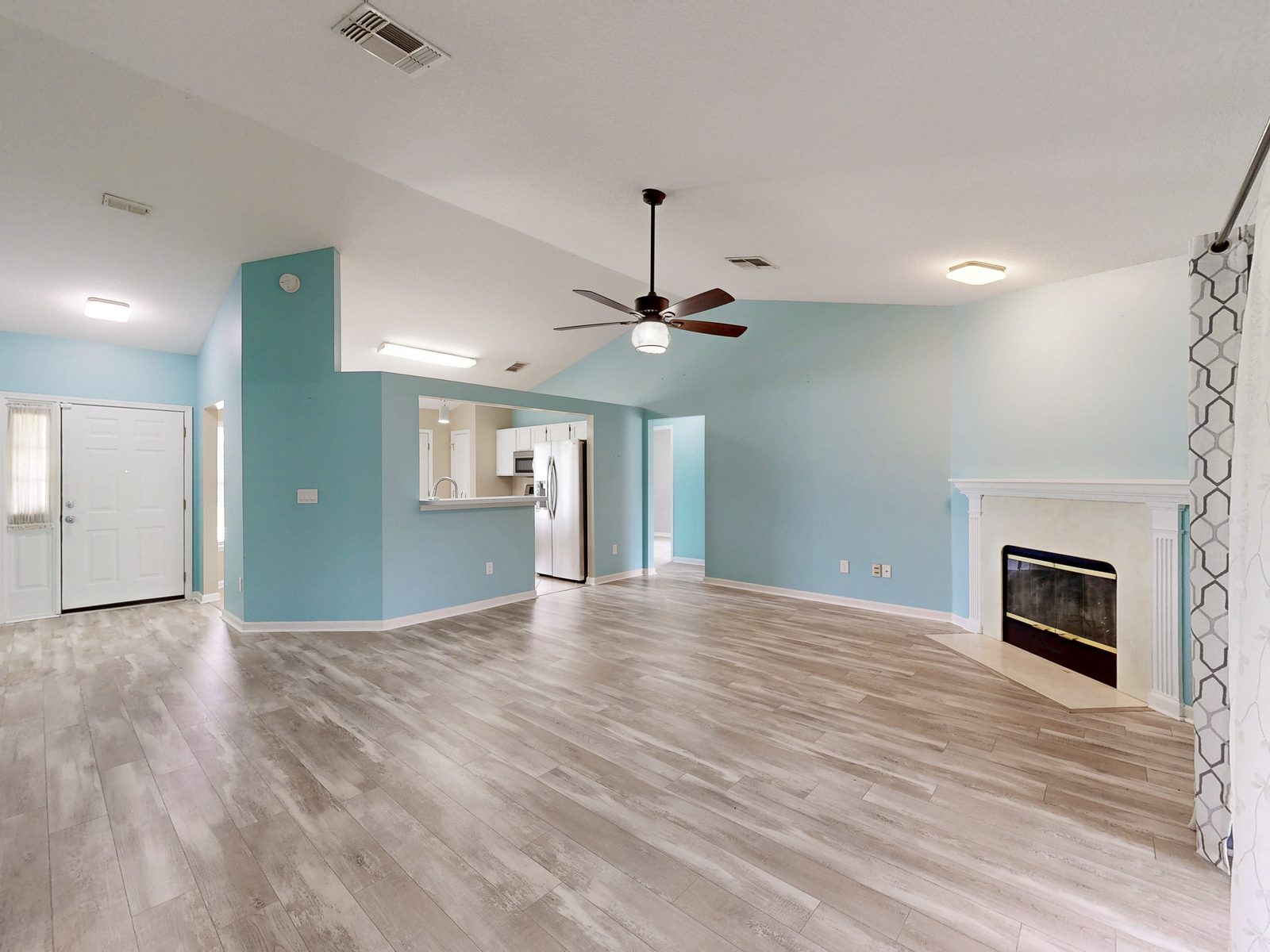 HDR photo of a coastal blue living room with fireplace and wood-look floors, exported from a Matterport scan, St. Johns County FL